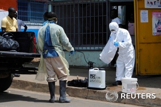 에볼라가 극성을 부리고 있는 라이베리아의 사망자 매장팀 직원이 지난 20일(현지시간) 몬로비아에서 동료에게 소독약을 뿌릴 준비를 하고 있다. /뉴스1 © News1 이기창