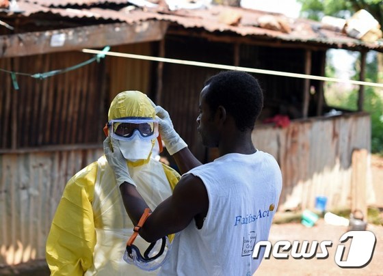 12일(현지시간) 한 시에라리온 적십자 대원이 에볼라 감염 사망자 시신 이송작업을 앞둔 동료 대원의 보호장비를 점검해주고 있다.© AFP=뉴스1 2014.11.13/뉴스1 © News1