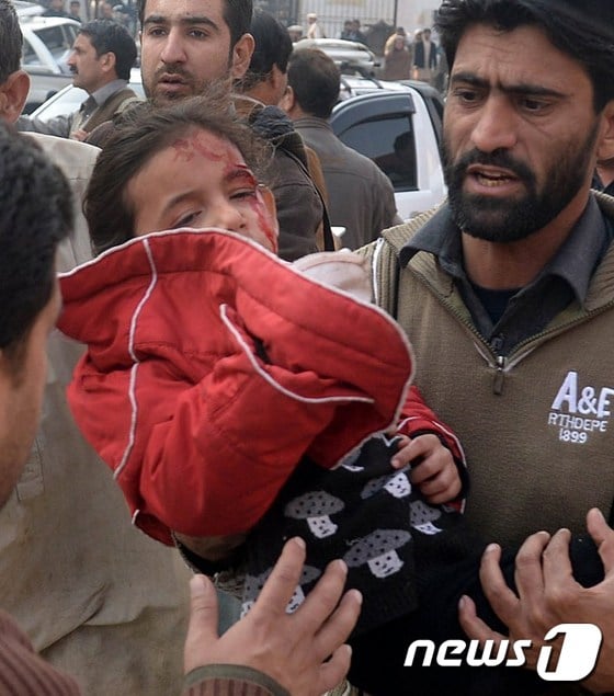 파키스탄 탈레반(TTP)가 16일(현지시간) 파키스탄 페샤와르의 군 부설학교를 공격했다. 한 남성이 총상을 입은 소녀를 옮기고 있다.© AFP=뉴스1
