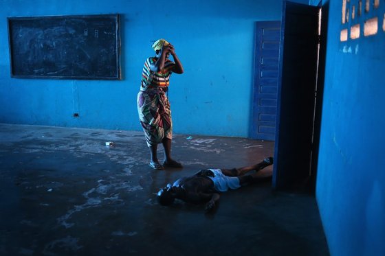 라이베리아에서 한 여성이 에볼라로 쓰러진 남편을 바라보고 있다. 에볼라 최초 발병국인 라이베리아는 올 7~8월부터 국경을 폐쇄하고 환자들을 격리했다. © 로이터=뉴스1 © News1