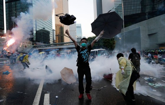 2014년 행정장관 직선을 요구하는 시위에서 한 청년이 경찰이 쏜 최루가스를 우산으로 막고 있다. 이후 시위는 ‘우산혁명’이라 불리게 됐다. © AFP=뉴스1