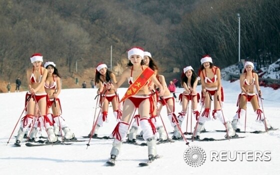 Women wearing bikinis and Santa Claus hats participate in a promotional event to celebrate the upcoming Christmas at a ski resort in Xuchang