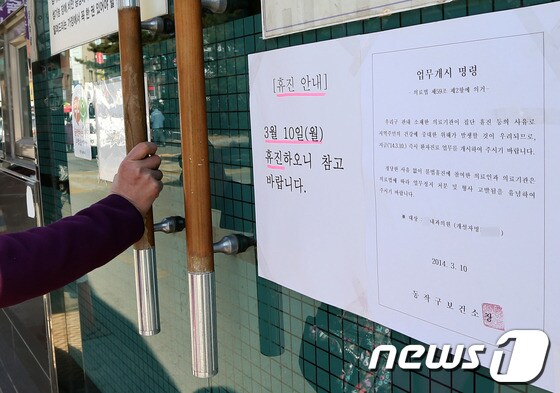 대한의사협회가 집단 휴진에 들어간 지난 2014년 3월 10일 당시 서울 동작구의 한 내과의원을 찾은 한 시민이 의원 측이 내건 휴진 안내와 보건소가 부착한 업무개시 명령이 나란히 붙은 출입문을 흔들어 보고 있다./뉴스1