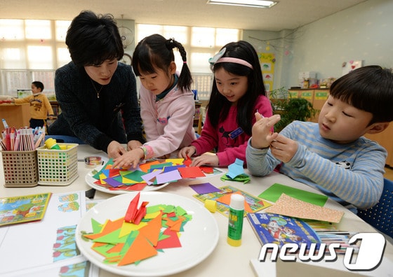 서울의 한 초등학교 돌봄교실에서 학생들이 선생님과 종이접기를 하고 있다. / 뉴스1 © News1