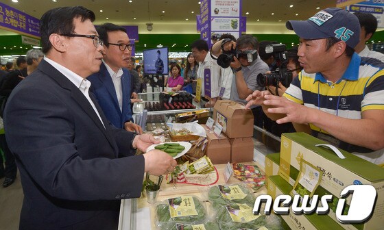 이동필 농림축산식품부장관(왼쪽)이 서울 양재 하나로마트에서 열리는 '농식품 6차 산업화 우수제품 기획 판매전'을 방문해 쑥떡을 들고 있다. © News1