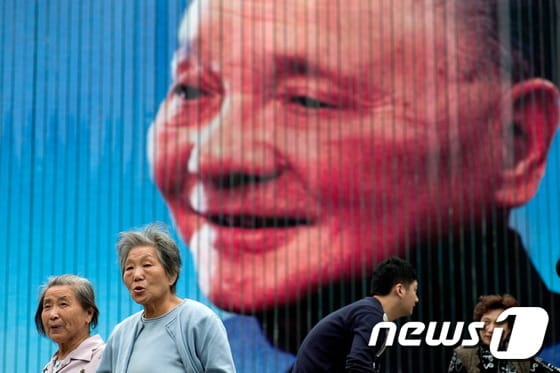 사람들이 덩샤오핑 전 중국 군사위원회 주석의 사진이 걸려있는 옥외 광고판을 지나가고 있다.  © AFP=뉴스1 © News1 정은지 기자