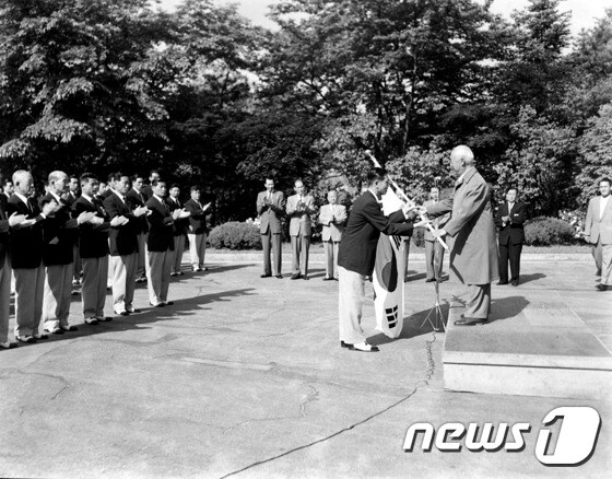 고 이승만 전 대통령이 1958년 도쿄아시안게임에 출전하는 선수들을 접견한 자리에서 태극기를 전달하고 있다.(국가기록원 제공)© News1