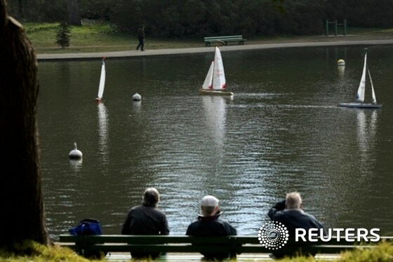 A group of men look on as their remote-controlled, model sail boats sail in Golden Gate Park in San Francisco