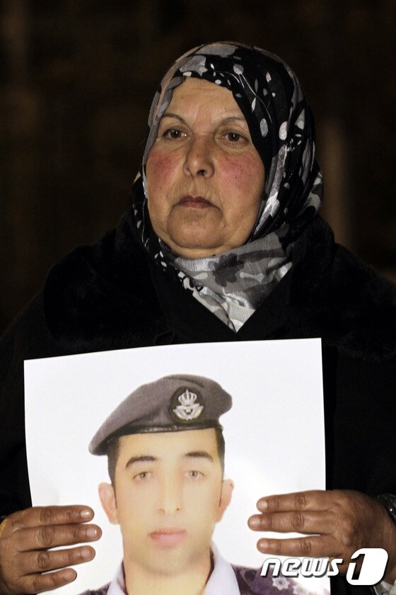 27일(현지시간) IS에 억류 중인 요르단 공군 중위 모아즈 유세프 알카사스베(27)의 모친이 아들의 사진을 들고 석방을 촉구하고 있다. © AFP=News1
