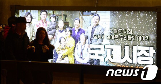관객들이 영화 '국제시장'의 대형 포스터 앞을 지나고 있다. 2015.1.4/뉴스1 © News1 한재호 기자