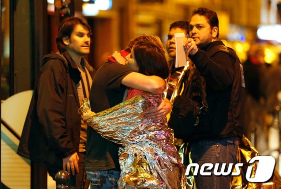 13일(현지시간) 프랑스 파리에서 발생한 연쇄 테러 현장에서 생존자들이 서로를 끌어안으며 안도하고 있다. © AFP=뉴스1