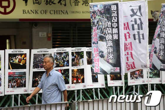 홍콩 남성이 센트럴점거 운동에 반대하는 포스터가 붙은 거리를 지나고 있다. ©AFP=뉴스1