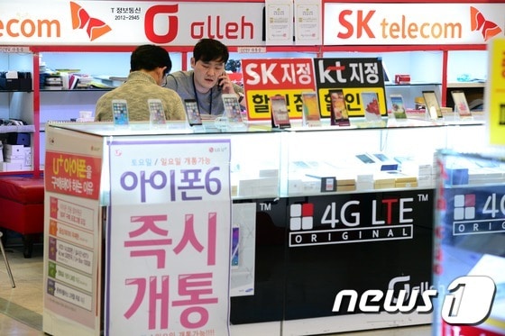 서울 시내 한 휴대폰 판매매장에서 점원이 손님에게 신규가입 절차를 안내하고 있다. 매장에는 '아이폰6 즉시개통' 문구가 걸려있다.  © News1 정회성 기자