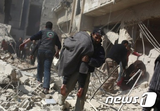 한 남성이 시리아 반군이 장악하고 있는 다마스쿠스 외곽 지역에서 부상자를 이송하고 있다. ⓒAFP=뉴스1
