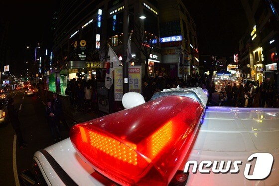 지난달 28일 밤 10시쯤 서울 마포구 홍대입구역 앞에서 근무 대기 중인 형사기동차량 옆으로 시민들이 지나가고 있다. © News1