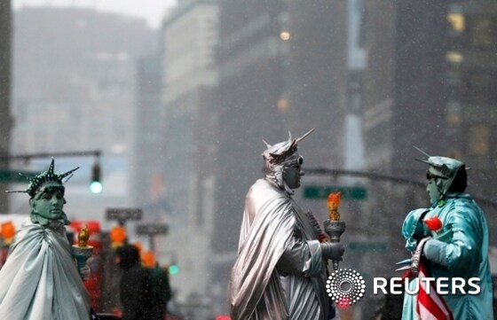 Street performers dressed as the Statue of Liberty stand during snowfall at Times Square in New York