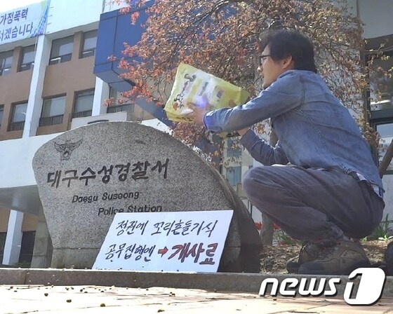 박근혜 대통령을 비난하는 전단지를 제작해 배포해 경찰의 출석요구에 응한 박성수씨가 21일 대구 수성경찰서 표지석에 개사료를 뿌리며 항의하고 있다./사진제공=박성수씨 © News1