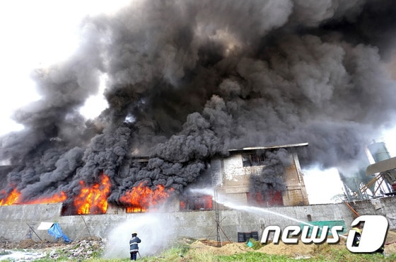 13일 필리핀 마닐라 북부 발렌주엘라의 고무 슬리퍼 공장에서 화재가 발생해 검은 연기가 치솟고 있다. © AFP=News1
