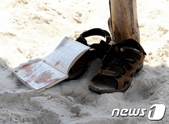26일 튀니지 휴양 도시 수스의 지중해 해변가에서 IS소행으로 추정되는 총격으로 다수의 유럽인들을 포함해 모두 39명이 숨졌다. 사진은 해변가의 총격 테러 현장에 남겨진 피가 묻은 책과 샌들.© AFP=News1
