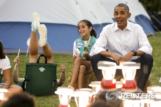 A Girl Scout loses her balance in her camp chair around pretend campfire as Obama and the first lady welcome scouts to camp-out on South Lawn of White House in Washington