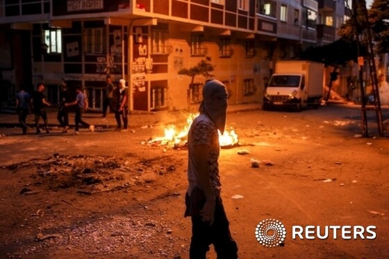 A far left-wing protester walks past a burning barricade during clashes with riot police in Istanbul