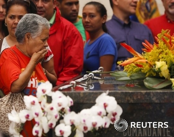 A woman blows a kiss to the tomb of Venezuela