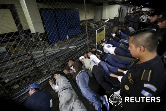 Gang members of the Mara Salvatrucha, (MS), criminal gang lie on the floor as police officers stand guard after a shootout in the basement of the Supreme Court of Justice in Guatemala City