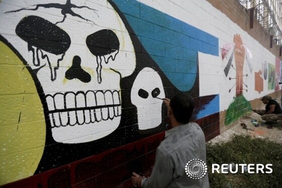 Pro-Houthi activist paints graffiti during a campaign against Saudi-led air strikes on the wall of the Saudi embassy in Sanaa