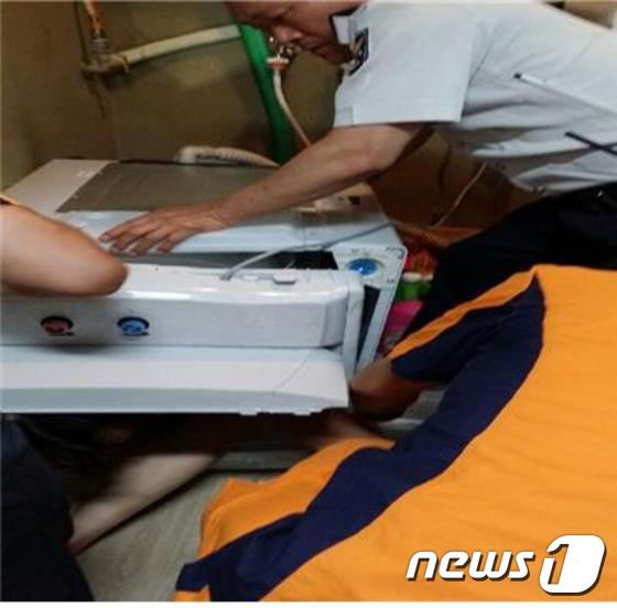 세탁기 뚜껑이 깨지면서 통 안에 빠져 나오지 못한된 피해 여성을 경찰이 구조하고 있다. © News1