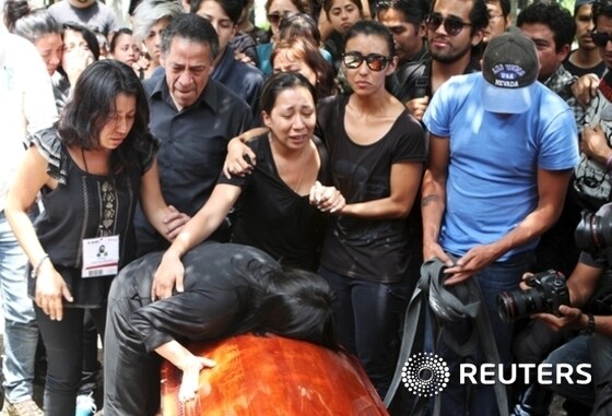 Relatives of late photojournalist Ruben Espinosa, mourn over his coffin at a cemetery in Mexico City