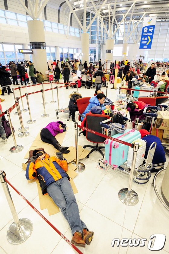 제주지역에 많은 눈이 내려 제주공항이 전편 결항된 가운데 24일 제주국제공항 대합실에 승객들이 종이상자를 펴고 잠을 자고 있다.2016.1.24/뉴스1 © News1 이석형 기자