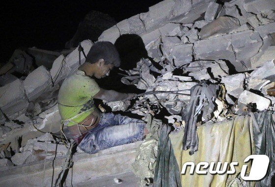 16일(현지시간) 시리아 알레포에서 한 소년이 공습으로 무너진 건물 잔해에 깔린 채 구조대를 기다리고 있다. © AFP=뉴스1
