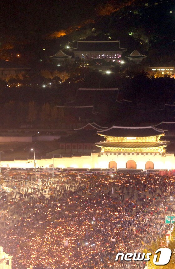 박근혜 대통령 퇴진을 요구하는 민중총궐기 대회가 열린 12일 밤 촛불을 든 광화문 광장의 시민들 뒤로 불켜진 청와대가 보인다.(사진공동취재단)2016.11.12/뉴스1 © News1 사진공동취재단