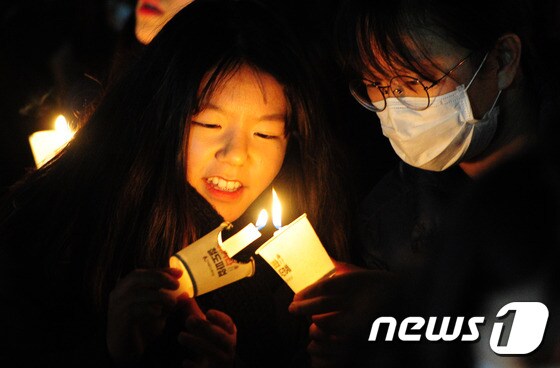 23일 오후 전북 전주시 오거리광장에서 열린 청소년 시국대회에 참가한 학생들이 촛불로 다른 초에 불을 밝히고 있다.2016.11.23/뉴스1 © News1 문요한 기자