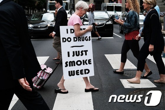 <br />민주당 전당대회(DNC)가 열린 지난 7월 28일(현지시간) 미국 펜실베이니아 필라델피아 시내에 한 여성이 마리화나 합법화를 지지하는 팻말을 들고 걸어가고 있다. © AFP=뉴스1