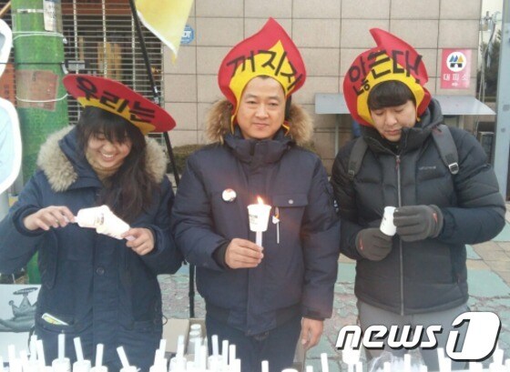 10일 오후 충북도청 서문 앞 도로에서 열린 충북 제3차 시국대회에서 '우리는 꺼지지 않는다'는  피켓을 쓴 시민들이 촛불을 나눠주고 있다. © News1