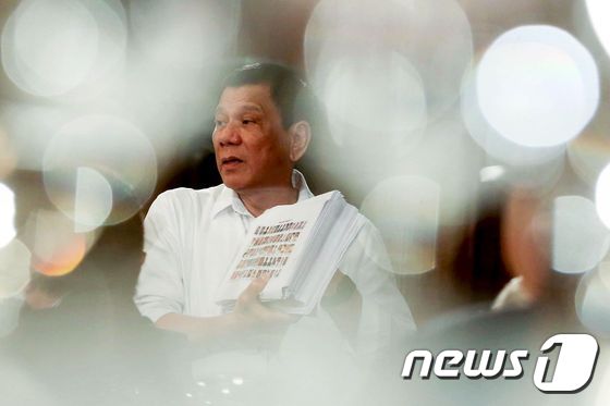 로드리고 두테르테 필리핀 대통령이 12일(현지시간) 말라카낭 궁에서 국내외 사업가들을 초청하고, '마약과의 전쟁'에 참가한 경찰과 정부 관계자의 명단을 보여주며 설명하고 있다. © AFP=뉴스1