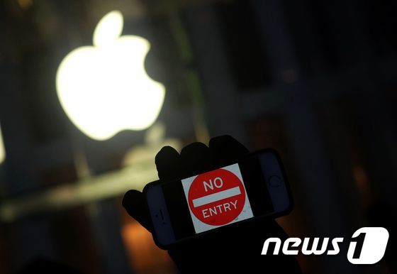 한 시위대가 미국 연방수사국(FBI)의 애플 '아이폰' 잠금 해제에 항의하는 시위를 전개하면서 뉴욕 애플스토어 인근에서 화면에 '접근 금지'라고 적힌 아이폰을 들고 있다. © AFP=뉴스1