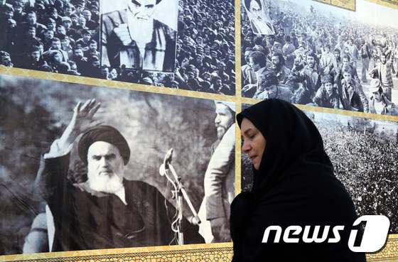 한 이란 여성이 테헤란에서 이란 이슬람 혁명의 아버지 아야톨라 루홀라 호메이니(1900∼1989)의 사진이 붙어 있는 입간판 앞을 지나고 있다. © AFP=뉴스1 © News1 최종일 기자