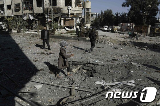 시리아의 한 소녀가 12일(현지시간) 수도 다마스쿠스 외곽 지역에서 걸어가고 있다. 주변은 공습으로 폐허가 돼 있다. © AFP=뉴스1