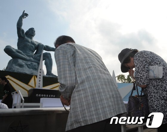 미군의 원자폭탄 투하 70년을 맞은 작년 8월9일 일본 나가사키의 평화공원 동상 앞에서 시민들이 원폭 희생자들을 추모하고 있다. © AFP=뉴스1