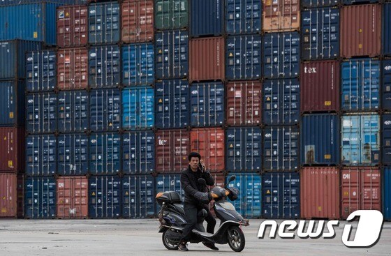 22일 (현지시간) 상하이 항의 높이 쌓인 컨테이너 야적장 앞을 오토바이를 탄 사람이 지나가고 있다.© AFP=뉴스1 © News1 우동명 기자