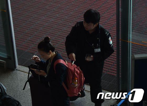 25일 베이징 공항 입구에서 검문 요원이 한 여성의 가방을 검색하고 있다.© AFP=뉴스1