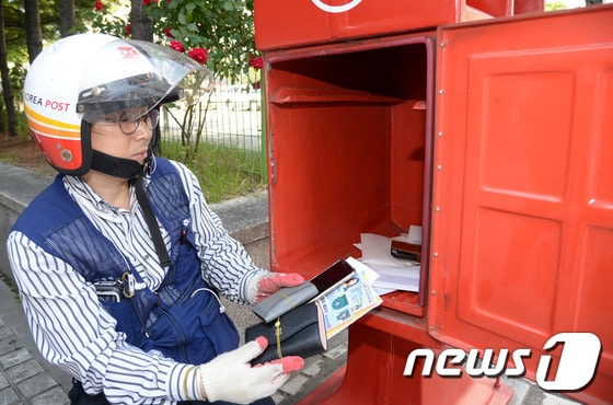 집배원이 우체통을 열어 우편물을 확인하는 모습 © News1