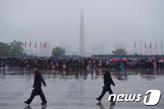 6일(현지시간) 북한 주민들이 비 내리는 김일성 광장에 모여있다. 멀리 북한의 '주체사상탑'이 보인다. 이날 오전 북한은 1980년 이후 36년만에 당대회를 개최했다. © AFP=뉴스1 © News1 이주성 기자
