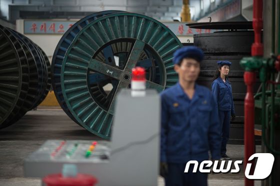 북한 평양에 있는 3월26일 공장에서 노동자들이 기계 옆에 서 있다. . © AFP=뉴스1 © News1 손미혜 기자