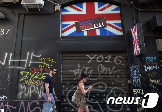 24일(현지시간) 그리스 아테네에서 영국 국기가 그려진 상점을 앞을 시민들이 지나고있다. © AFP=뉴스1