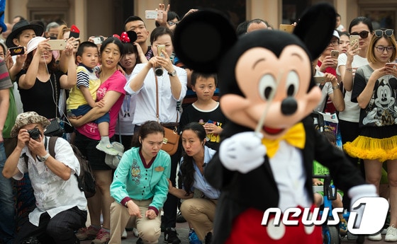  중국 상하이 디즈니랜드에서 관람객들이  퍼레이드를 진행중인 미키마우스 사진을 찍고 있다. © AFP=뉴스1