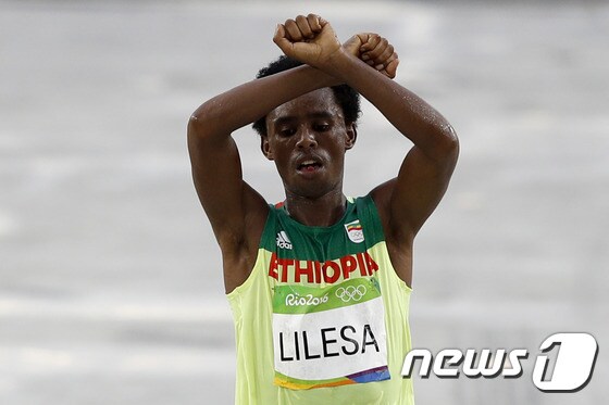 에티오피아의 페이사 릴레사가 지난 21일(한국시간) 열린 2016 리우 올림픽 남자 마라톤에서 손으로 'X'자를 표시하면서 결승선을 통과하고 있다. © AFP=News1