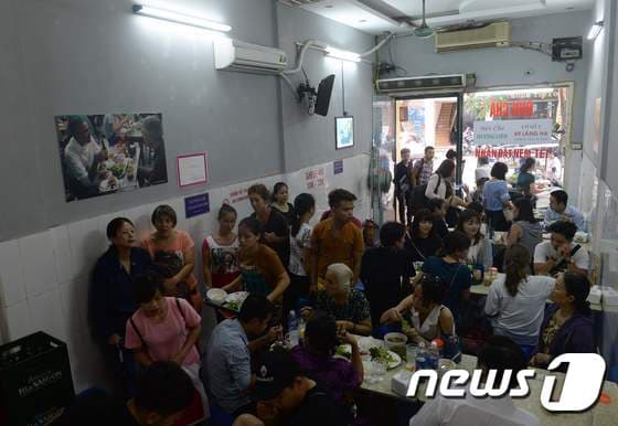 베트남 하노이 분짜 식당 냐항흐엉리엔에 사람들이 가득 차 있다. 옆에는 식사하는 버락 오바마 미국 대통령이 사진이 붙어 있다. © AFP=뉴스1